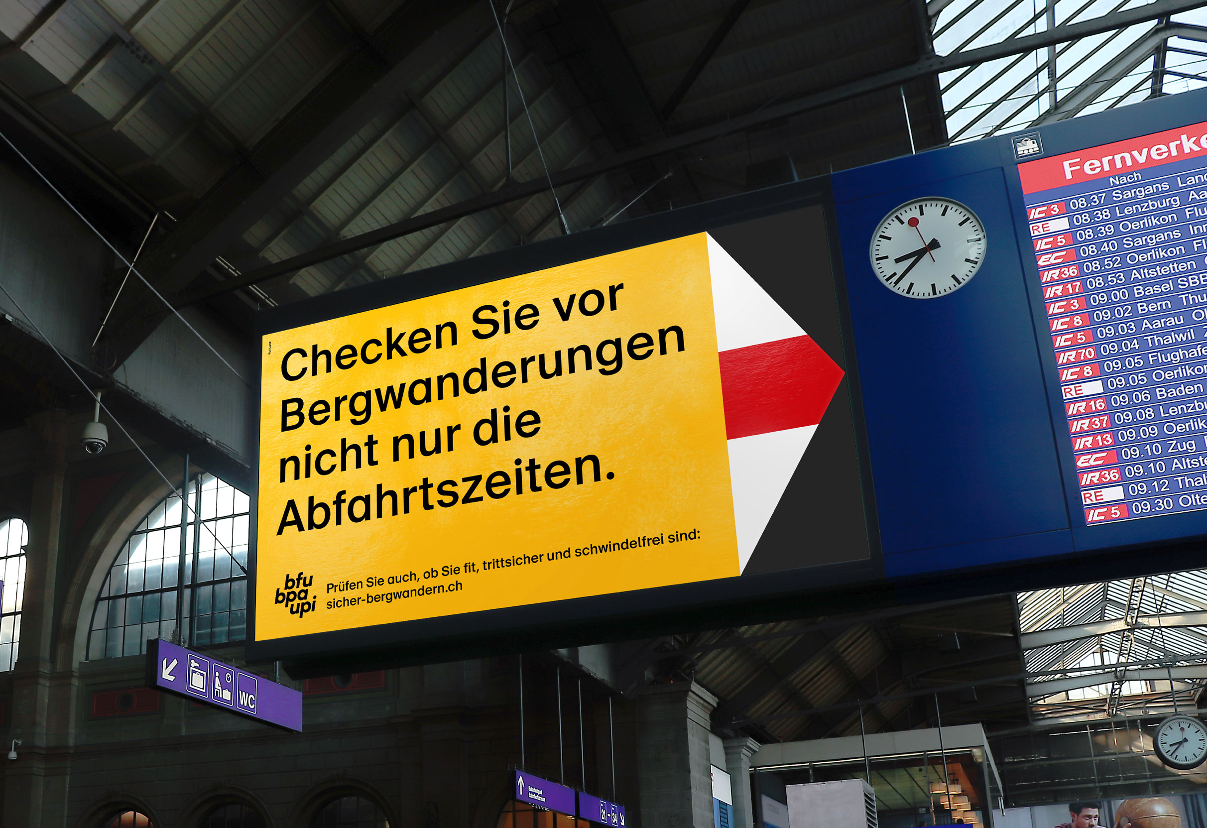 Übergrosser Bergwanderweg der im Zürcher Hauptbahnhof auf die Abfahrtsanzeige gerichtet ist: Checken Sie vor Bergwanderungen nicht nur die Abfahrtszeiten.